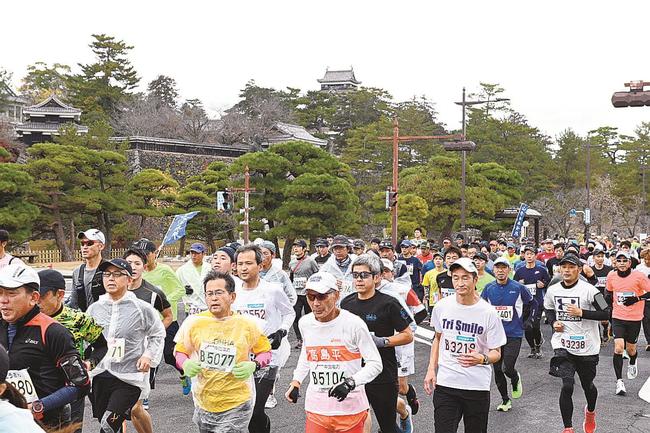 国宝松江城を背後に、力走するランナーたち＝松江市殿町