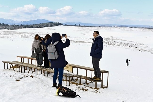 雪で真っ白になった鳥取砂丘で写真撮影する観光客＝鳥取市福部町湯山、鳥取砂丘