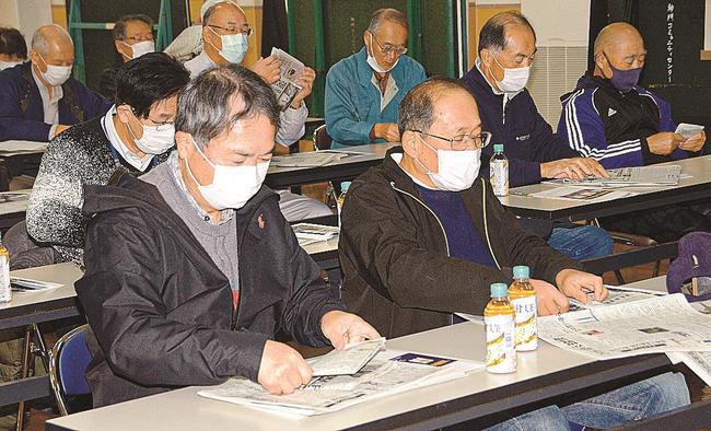 新聞を細かく折りたたむ参加者＝出雲市知井宮町、神門コミュニティセンター