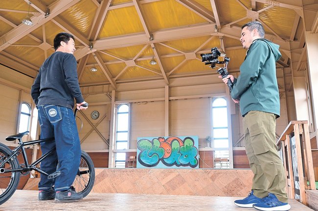 廃校になった旧小学校分校を活用したＢＭＸ専用パークを取材するグレッグ・ラムさん（右）＝鳥取県江府町大河原、ｂｉｇ　ｍｏｕｎｔａｉｎ　ｒｏｏｍｓ