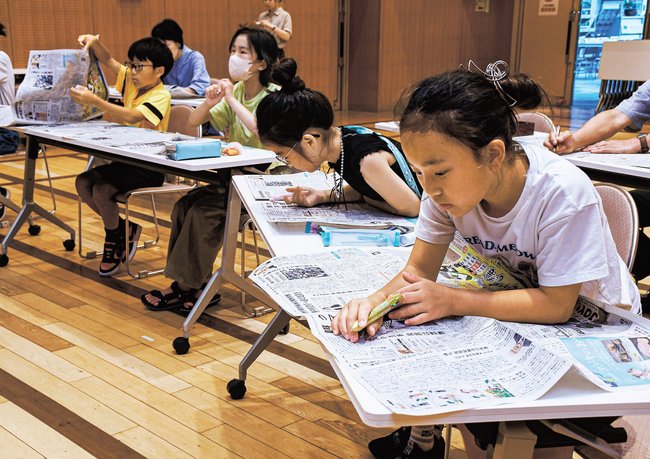 紙面から文字を探すゲームに挑戦する児童＝松江市西川津町、川津公民館