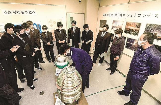 海上保安官（中央）から灯台の資材について説明を受ける境港総合技術高校の３年生ら＝境港市花町、海とくらしの史料館