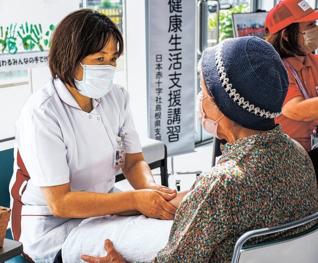看護師（左）のハンドケアを受ける来院者＝松江市母衣町、松江赤十字病院