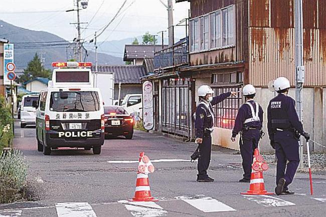 事件があった現場付近を規制する警察官＝２５日午後６時５５分、長野県中野市