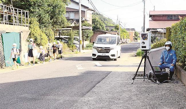 児童が登校する中、可搬式の速度違反取り締まり装置を使い、違反に目を光らせる松江署員＝松江市東出雲町下意東