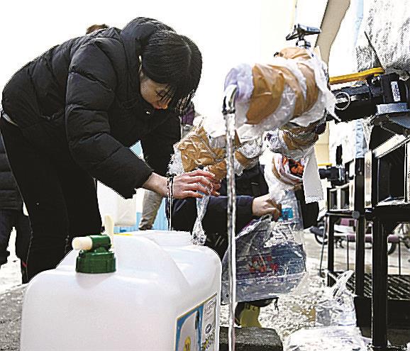 石川県輪島市で給水を受ける女性。被災地では水道管や浄水設備が損傷し、続く断水が大きな課題になっている＝１４日