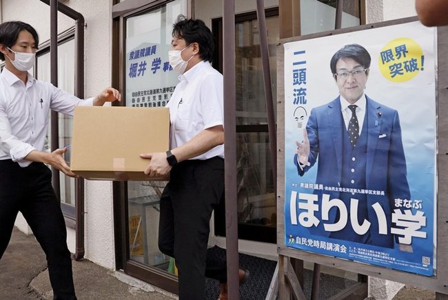堀井学衆院議員の地元事務所を家宅捜索し、押収物を運び出す係官ら＝１８日午後、北海道登別市