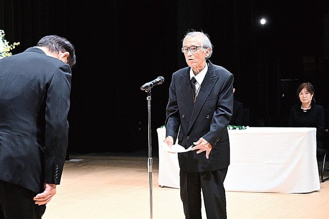 遺族会を代表して田中武夫市長（左）に謝辞を述べる上廻芳和さん＝安来市飯島町、市総合文化ホール・アルテピア