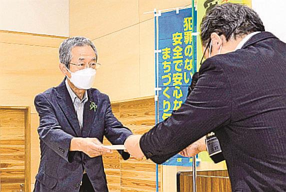 悪質商法・特殊詐欺撃退モデル地区の指定書を受け取る本田貢久会長＝出雲市湖陵町二部、湖陵コミュニティセンター