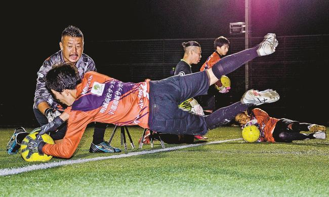 体を投げ出してボールを止める技術を指導する鈴木勝久さん（左奥）＝浜田市上府町、サン・ビレッジ浜田