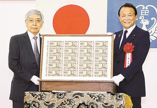 刷り上がった新１万円札を手にする麻生財務相（右）と日銀の黒田総裁＝１日午後、東京都北区の国立印刷局東京工場（国立印刷局提供）