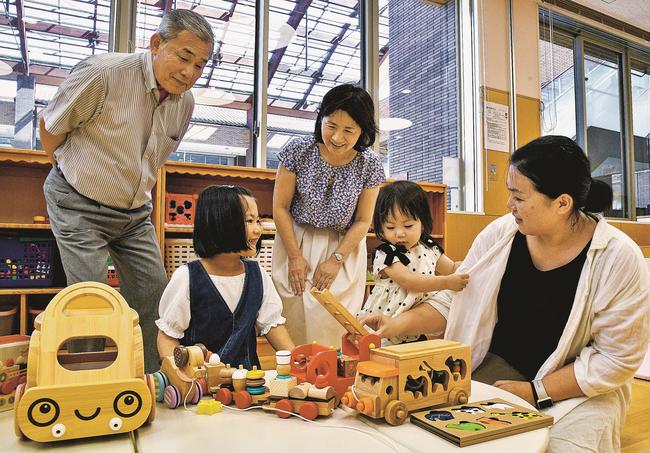 木製おもちゃで遊ぶ親子の様子を見守るしちだ・教育研究所の七田真裕美副社長（左から３人目）ら＝江津市江津町、市子育てサポートセンター