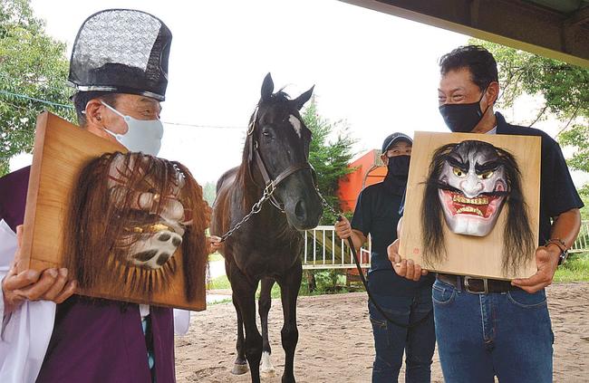 引退競走馬のたてがみで作られた出雲神楽のお面を披露する関係者＝鳥取県大山町赤松、大山乗馬センター