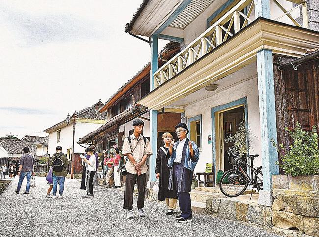 黒川聡会長（右）の解説に耳を傾けながら、古い街並みを散策する参加者＝江津市江津町