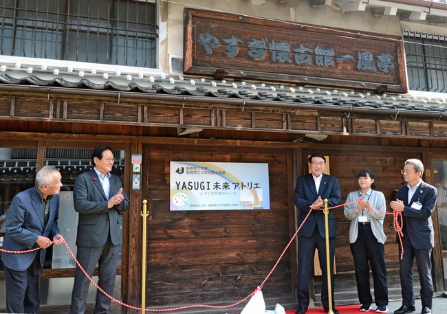 看板の除幕をして開設を祝う田中武夫市長（左から２人目）、清原正義学長（同３人目）ら＝安来市安来町、やすぎ懐古館一風亭