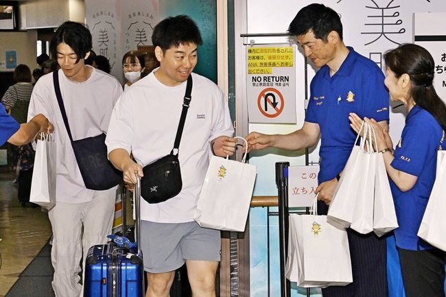 山本浩章益田市長（右から２人目）から記念品を受け取る搭乗客＝益田市内田町、萩・石見空港