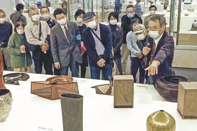 展示作品の特徴を来館者に説明する三浦信一さん（右）＝松江市袖師町、島根県立美術館