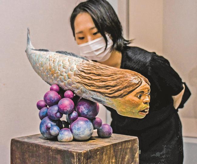 男性の頭をした人魚を精巧に表した「リアルマーメイド」に見入る来場者＝鳥取県日南町霞、町美術館