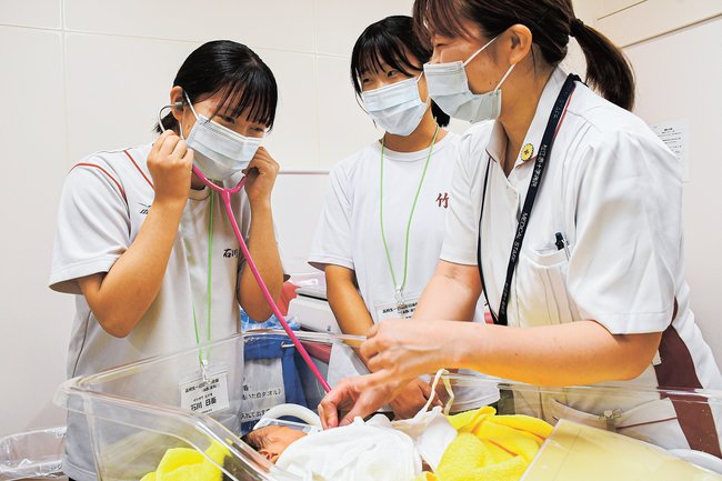 助産師に教わりながら赤ちゃんの心拍を聴く高校生（左）＝松江市母衣町、松江赤十字病院