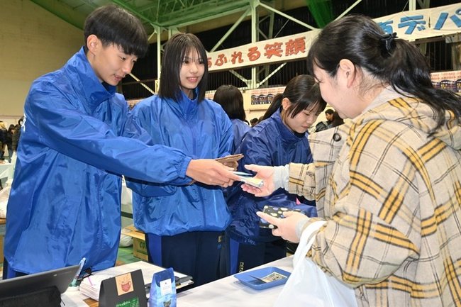 来場者に商品を渡す生徒＝浜田市熱田町、浜田商業高校