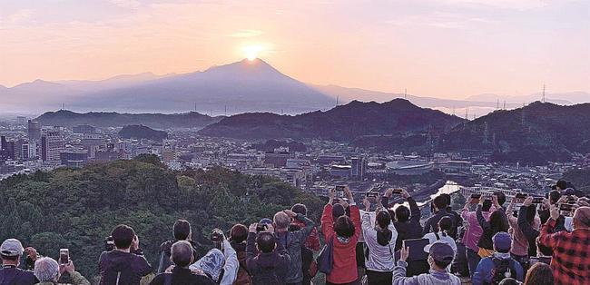 「ダイヤモンド大山」を写真に収める参加者＝２３日午前６時４４分、米子市久米町、米子城跡