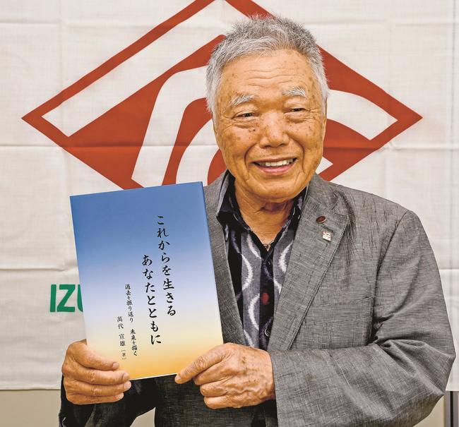 出版した本を手にする萬代宣雄さん=出雲市矢野町