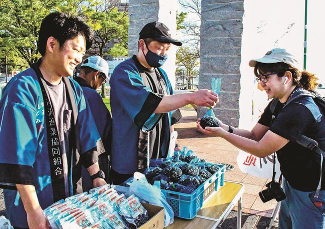 来場者にシジミを配る宍道湖漁業協同組合の組合員（中央）＝松江市袖師町、岸公園