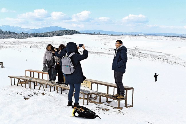 雪で真っ白になった鳥取砂丘で写真撮影する観光客＝鳥取市福部町湯山