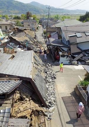 最大震度７を観測した熊本地震で倒壊した家屋のそばを歩く人たち＝２０１６年４月１５日、熊本県益城町（小型無人機から）
