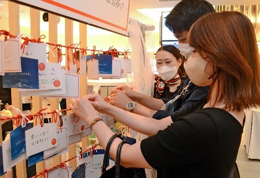 願い事を書いた額を「絵馬掛け」に結ぶ来館者=東京都千代田区、日比谷しまね館