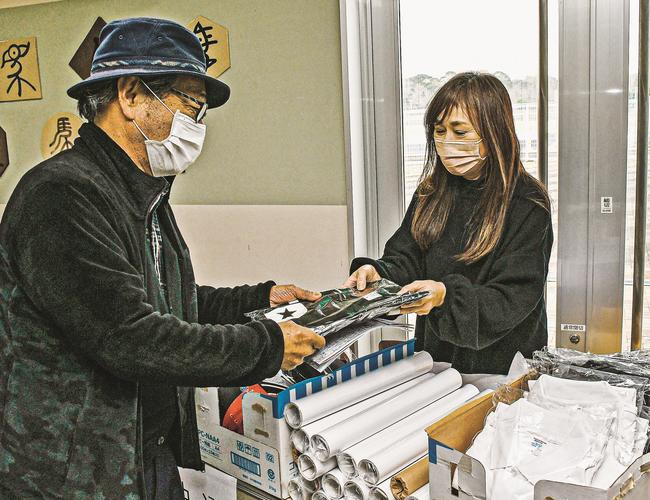 記念グッズを受け取る来場者（左）＝益田市高津４丁目、大井競馬場益田場外発売所