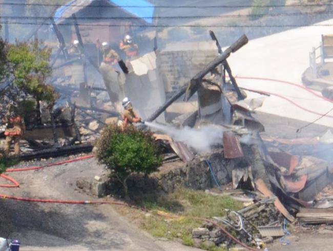 焼けた建物に放水する消防署員＝１０日午後１時半、出雲市佐田町東村