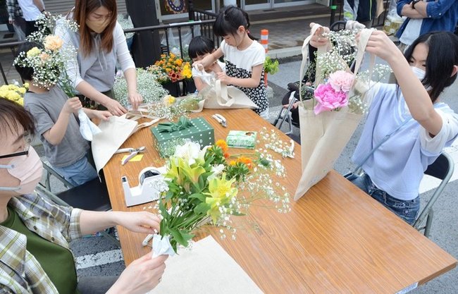 好みの花を切りそろえて袋に入れ、花束を作る参加者＝鳥取市弥生町、若桜街道