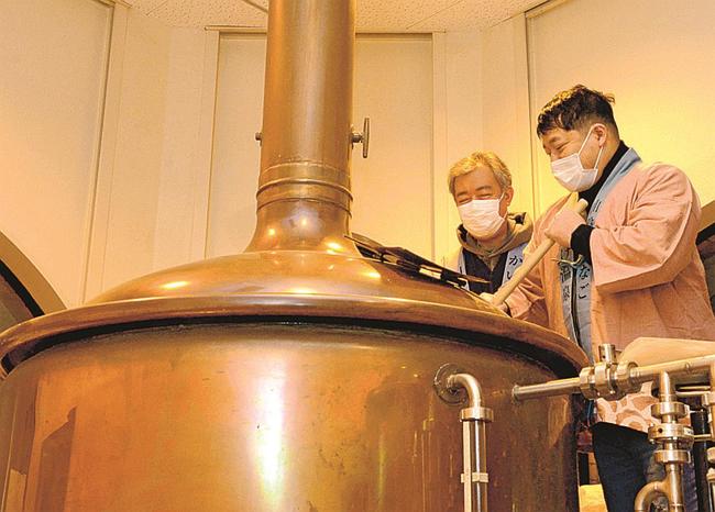 仕込み釜に投入した原料をかき混ぜる皆生温泉旅館組合の関係者たち＝鳥取県伯耆町丸山、久米桜麦酒
