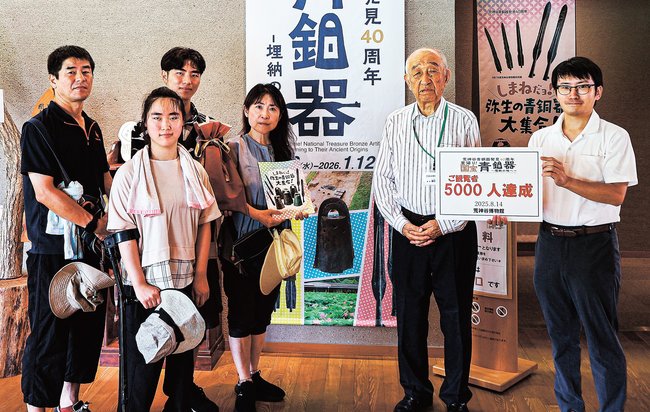 ５千人目の武田万希子さん（左から４人目）らを歓迎する関係者＝出雲市斐川町神庭、荒神谷博物館