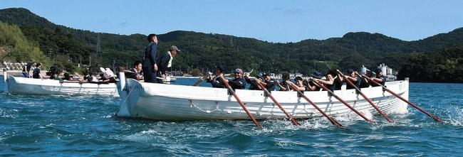 息を合わせて力強くオールをこぐ参加者＝島根県隠岐の島町東郷、西郷湾