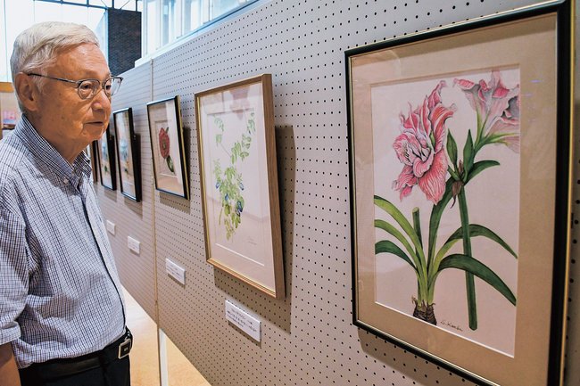細密に描かれた植物画を鑑賞する来場者＝出雲市斐川町直江、ひかわ図書館ホール