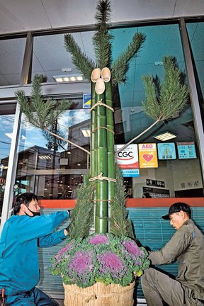 高さ約４メートルのジャンボ門松を飾り付ける参加者＝益田市常盤町、キヌヤ益田ショッピングセンター