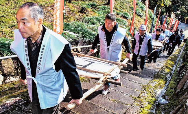直径８０センチの大餅を持ち、観音堂に続く石段を上る地元住民＝雲南市三刀屋町多久和、寿福寺