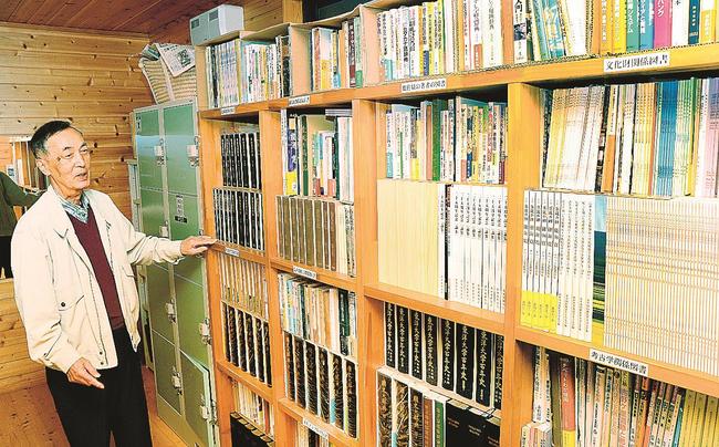 脱衣所の棚に収蔵された能海寛や島村抱月の関連図書などを紹介する隅田正三組合長＝浜田市金城町波佐、ほたる湯館
