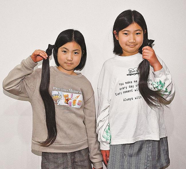ヘアドネーションのために切った髪を手にする原田悠楓さん（右）と妹の莉桜さん＝益田市中島町