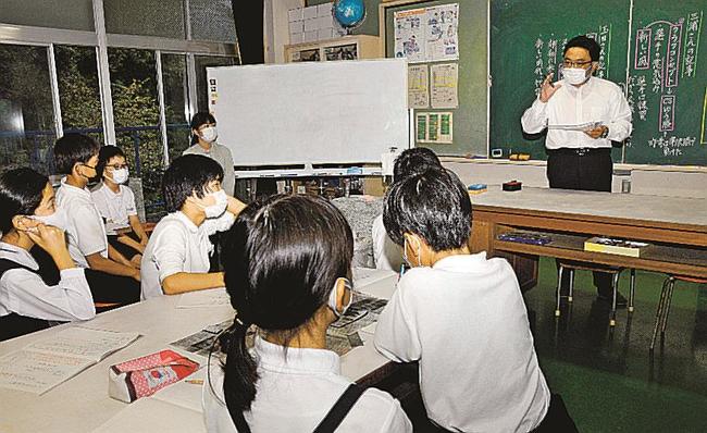記事に込めた思いを児童に語る山陰中央新報社の三浦純一記者（右）＝松江市八幡町、竹矢小学校