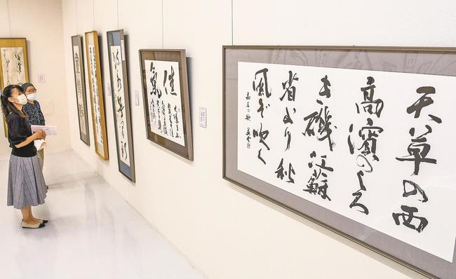 一流の書家の巧みな筆遣いに見入る来場者＝米子市中町、市美術館