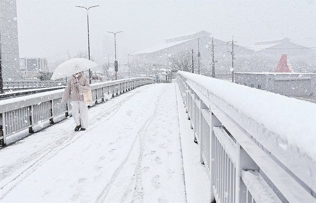 雪が積もった道を歩く通行人=21日午前10時25分、松江市西川津町、くにびき大橋