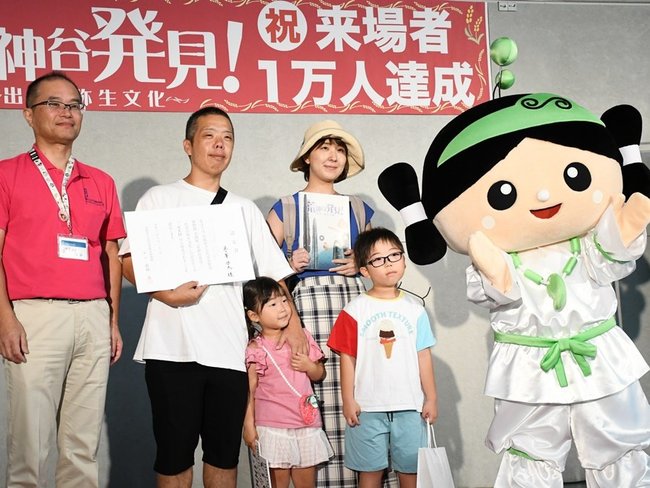入場１万人目の認定証を手にする正ヶ峯啓太さん（左から２人目）＝出雲市大社町杵築東、島根県立古代出雲歴史博物館