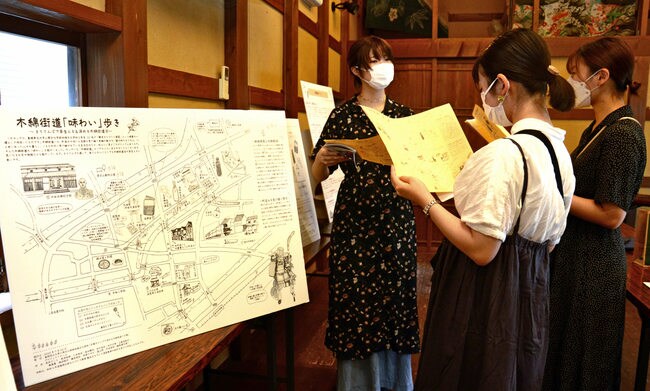 来場者に完成したマップを紹介する学生（左）＝出雲市平田町、木綿街道交流館