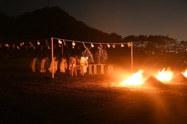 かがり火がたかれる中、神事を執り行う神職たち＝２２日午後７時７分、出雲市大社町杵築北、稲佐の浜