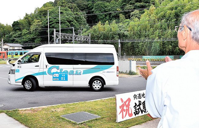 見送りを受けて走り出すＡＩデマンドバス＝松江市宍道町宍道、宍道公民館
