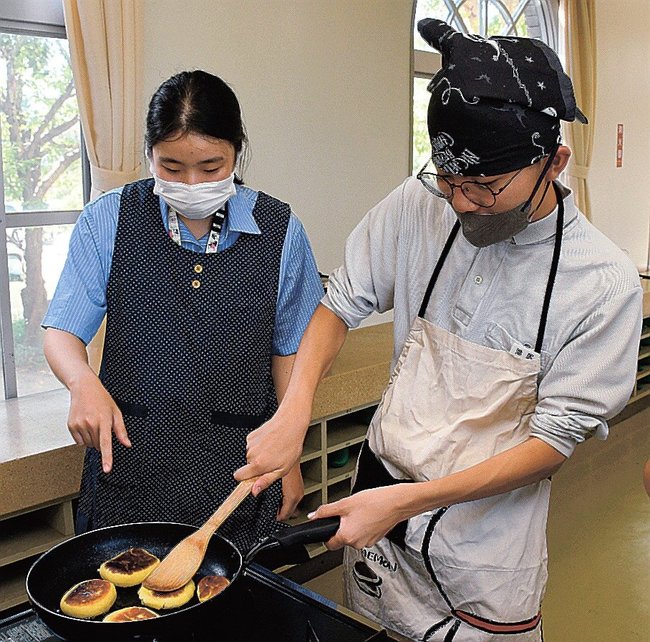 パク・ソヨンさん(左)から焼き加減を教わる生徒=出雲市西林木町、出雲北陵中