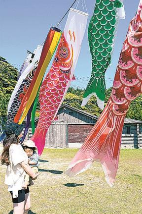 飾り付けられたこいのぼりを見る親子＝島根県隠岐の島町久見、多目的共同利用施設